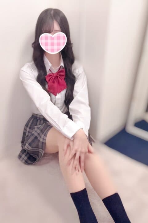 すみなは白いシャツにチェックのスカート、赤いリボンをつけて微笑んでいる。