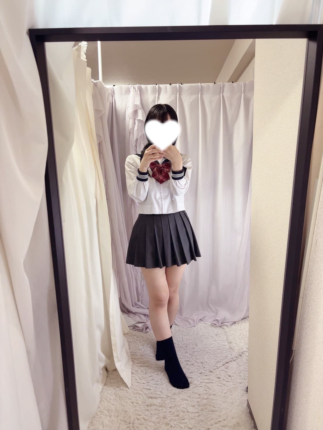 あいがスカート姿で鏡の前に立ち、微笑んでいる姿。
