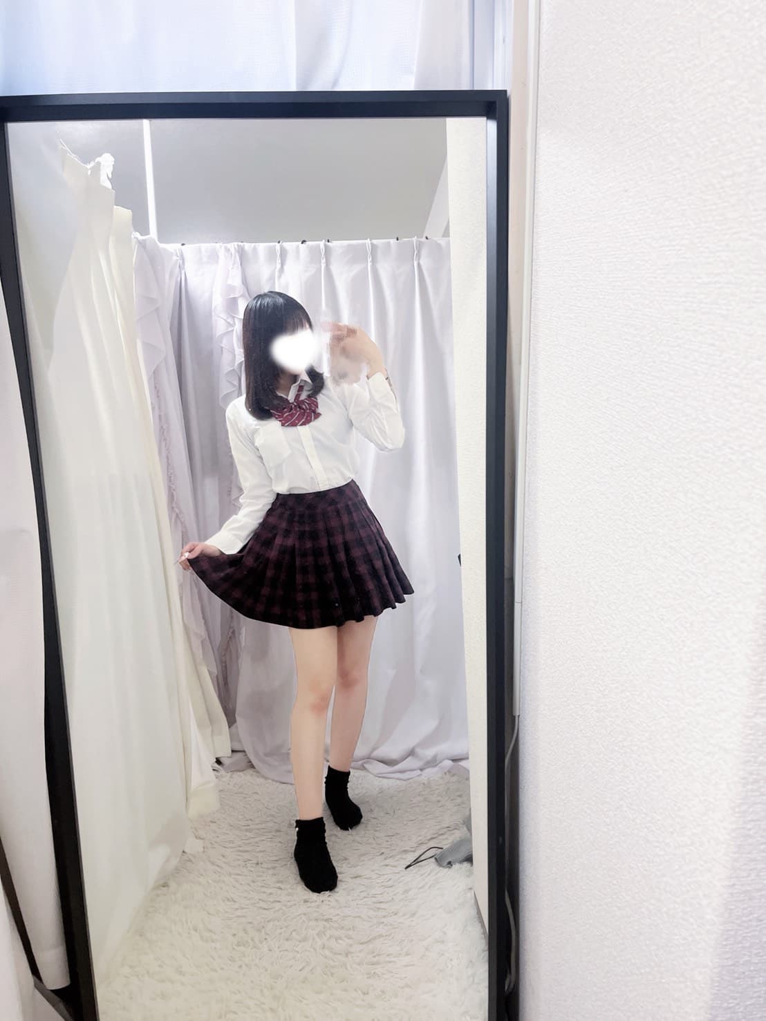 10/14体験入店初日ひな、白いシャツとチェック柄スカートで笑顔。背景はカーテン。