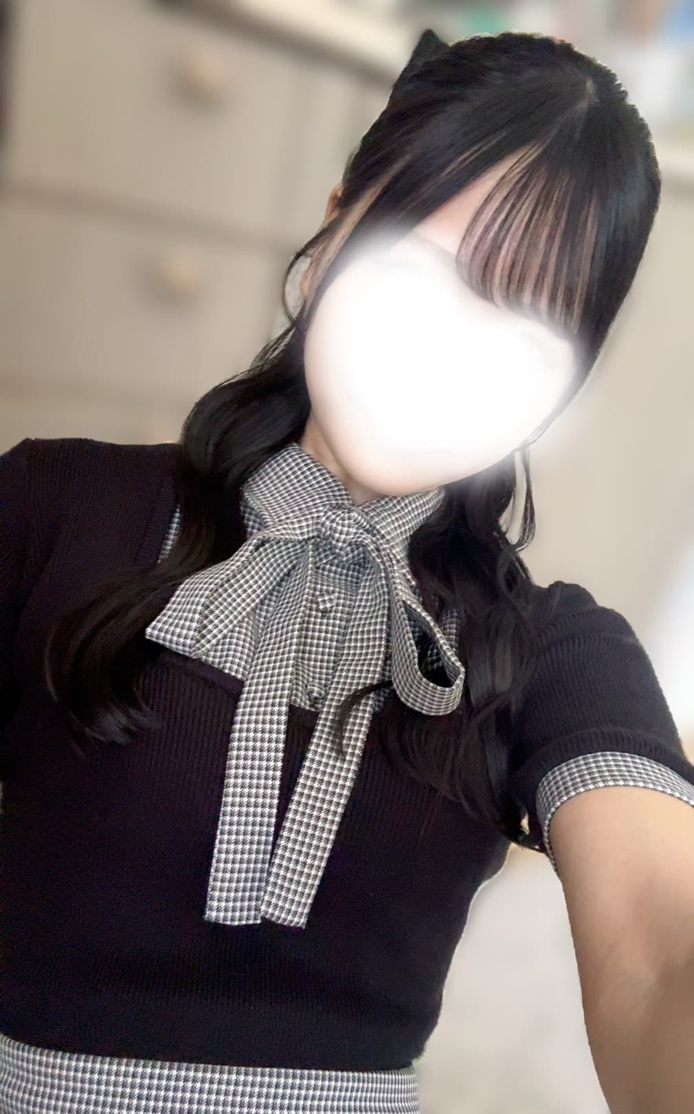 そらねは黒のトップスにリボンを付け、微笑みを浮かべている。
