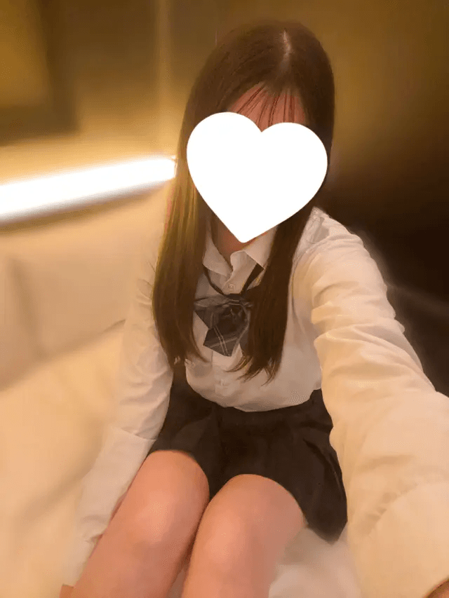 はるのが白いシャツとスカートを着て微笑む姿。背景は柔らかな照明。