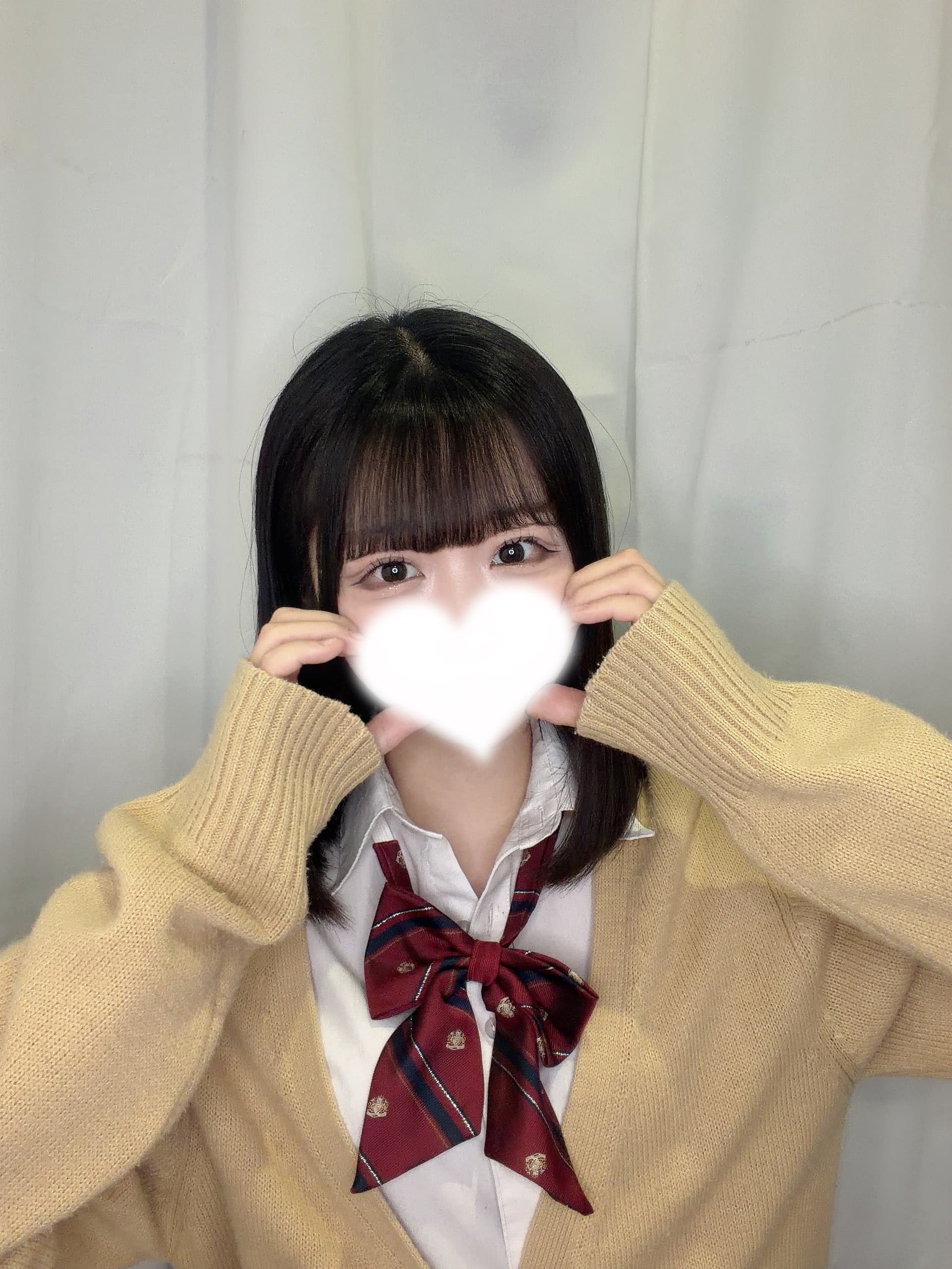 ゆかがセーラー服で微笑みながらハートを作っている。