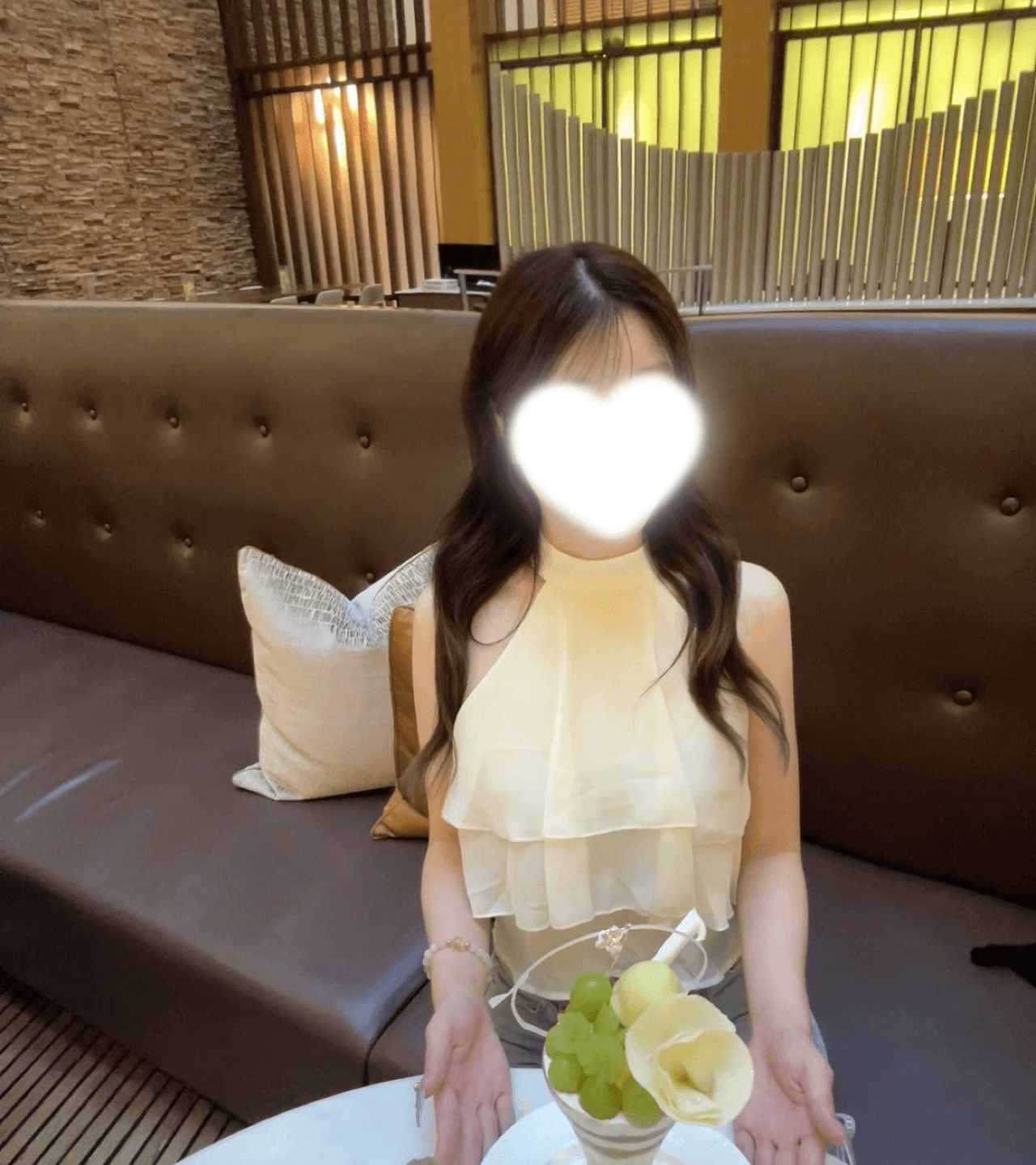 ももあが白いブラウスを着て微笑みながらフルーツを前に座っている。
