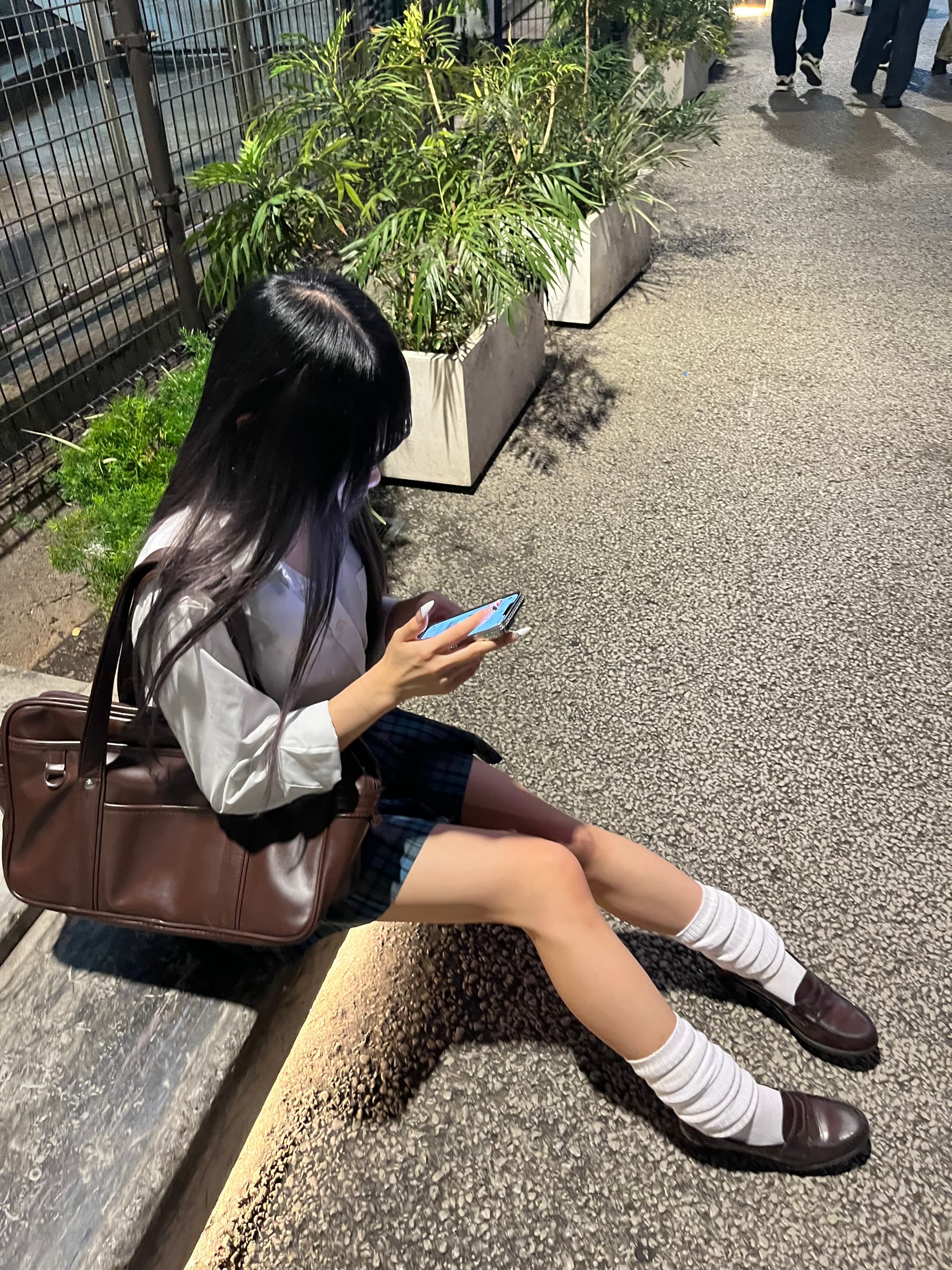 わたがスマートフォンを見ながら座っている夜の街並み。