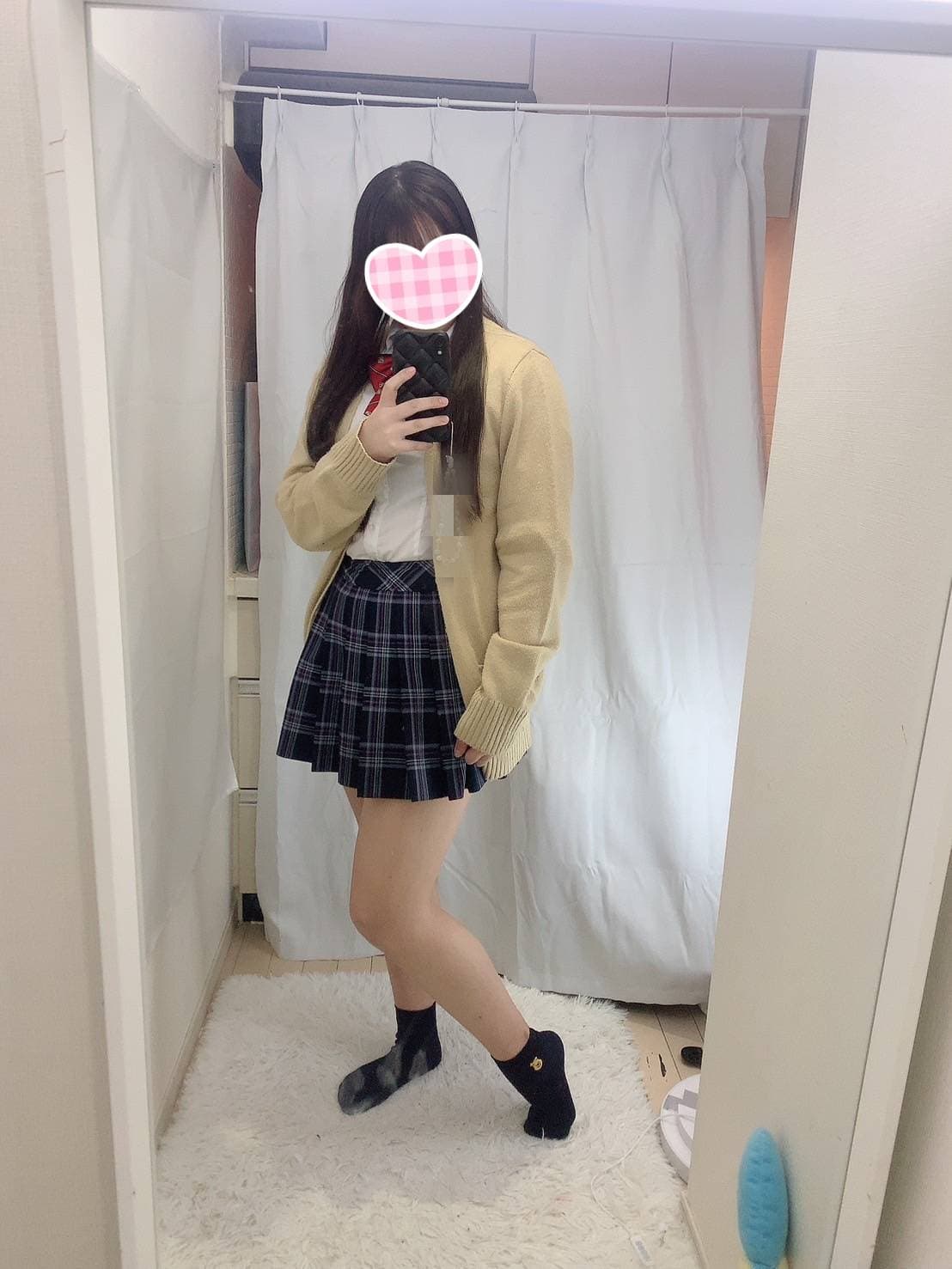 ゆめのは、カーディガンとチェックのスカート姿で鏡の前に立っている。