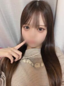 れんはストライプの服を着て、指を口に当てて微笑んでいる。