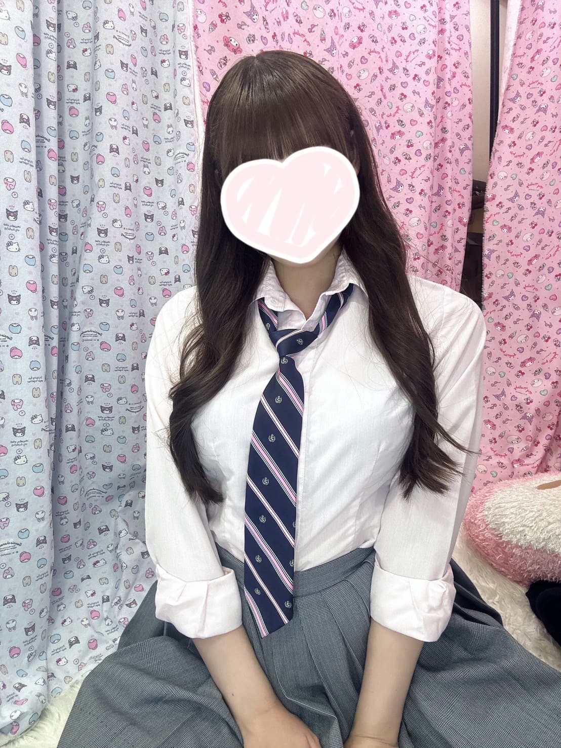 りあらは白いシャツにネクタイ、グレーのスカート姿で微笑んでいる。