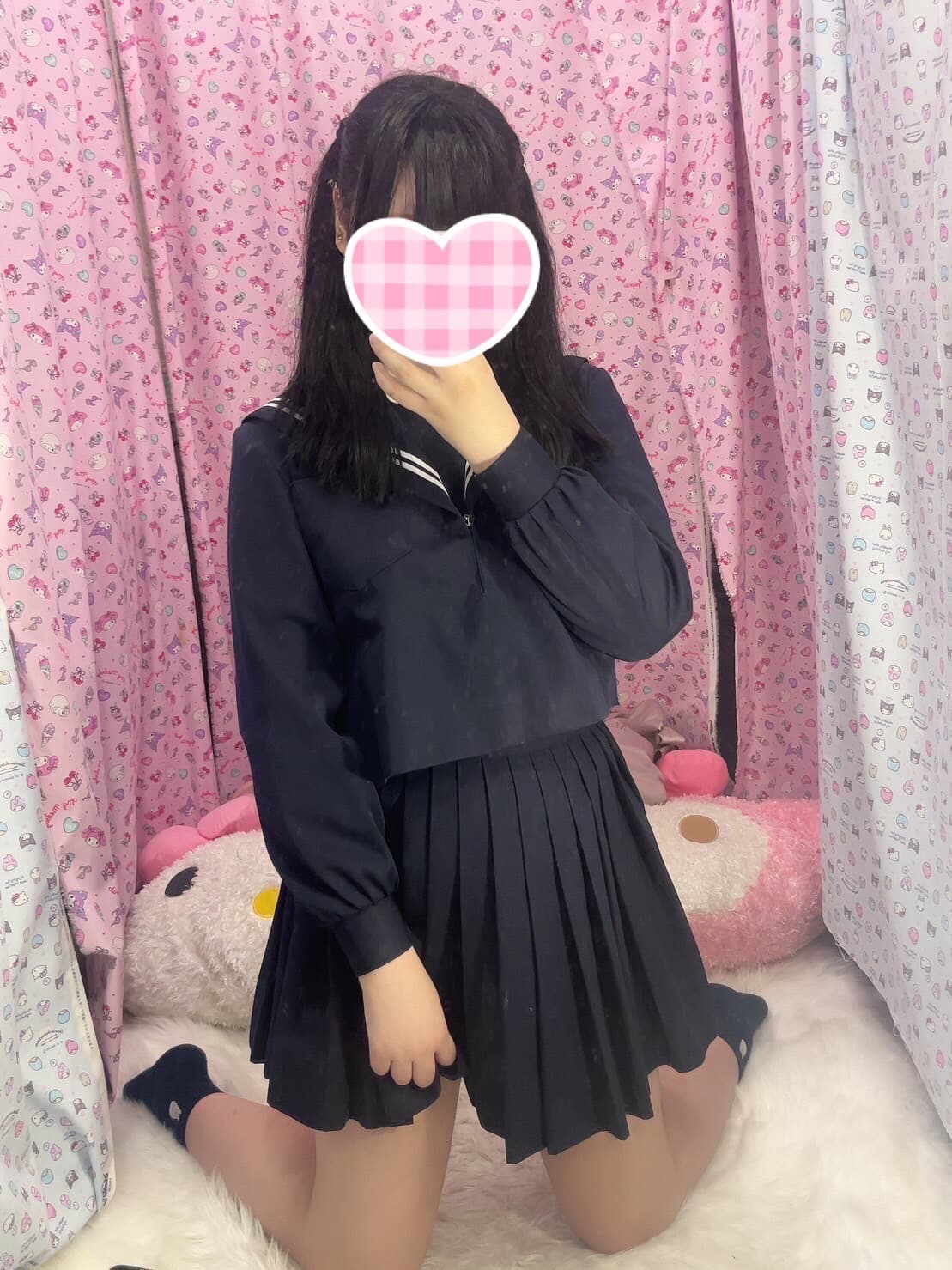 ねねが黒の制服を着て、ピンクの背景でポーズを取っている。