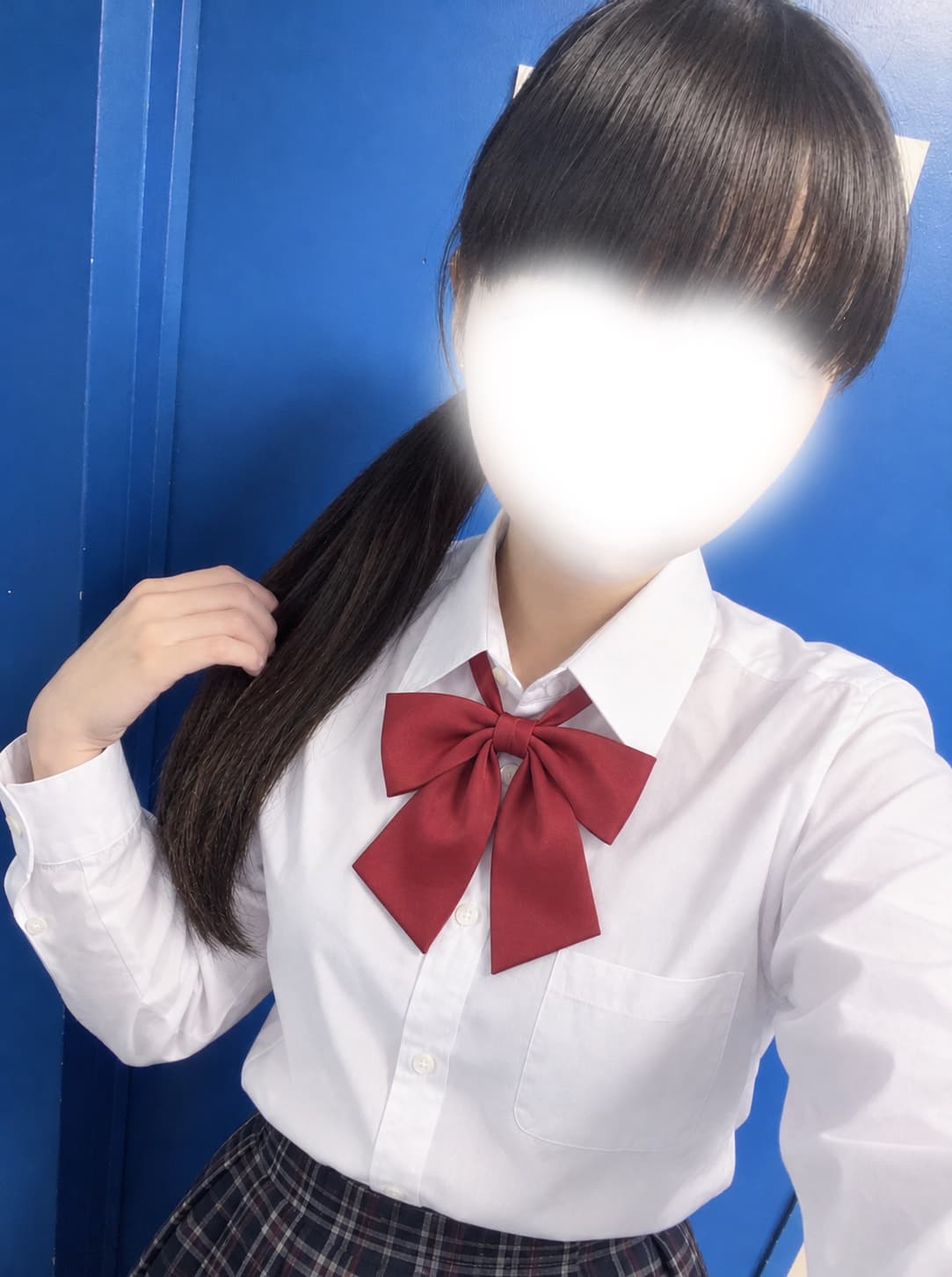 てん【8月度新人ランキング1位】が赤いリボン付き制服を着て、青い背景の前でポーズをとっている。