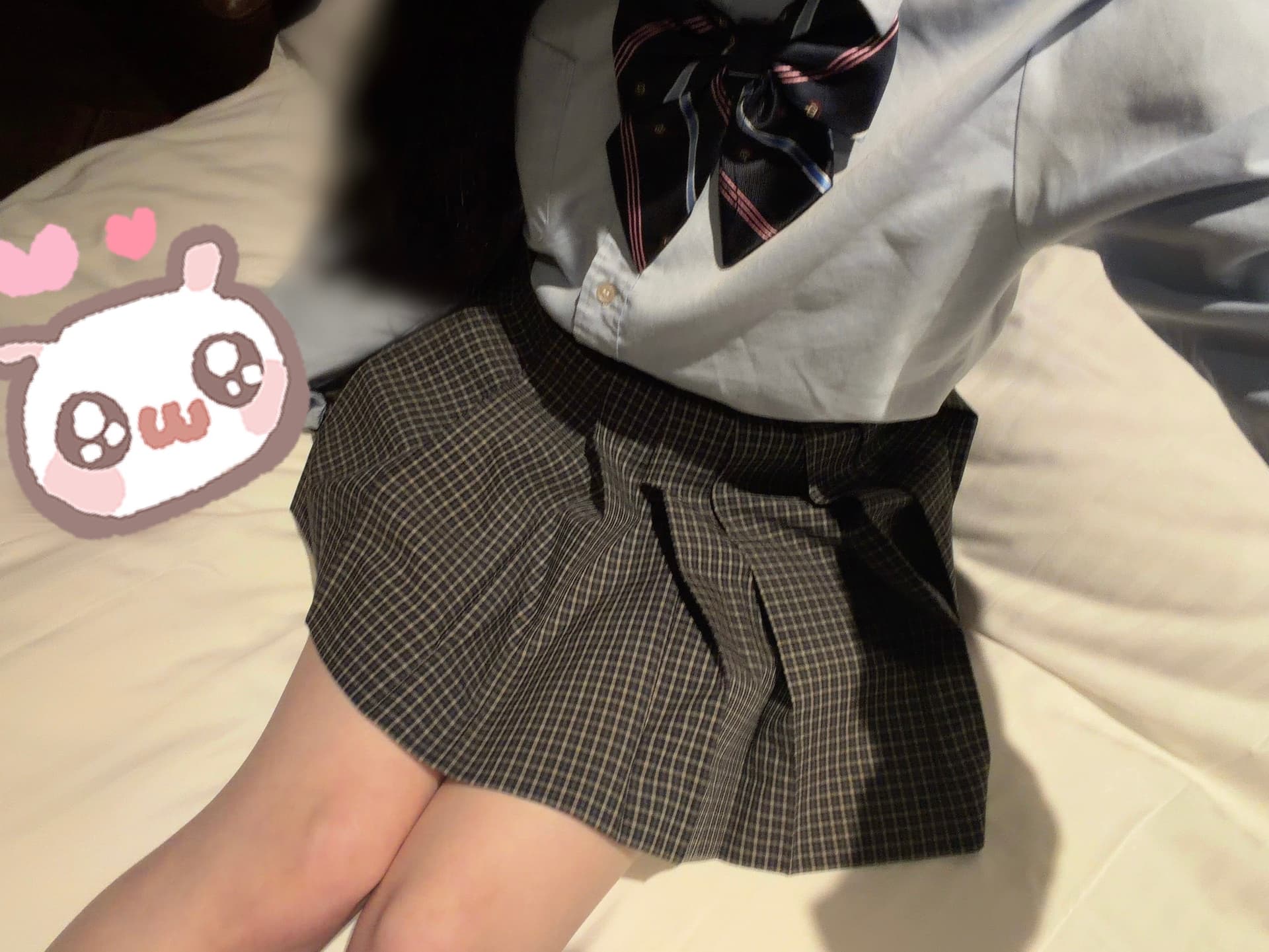 「みくりが制服を着てベッドに座り、笑顔を見せている。」