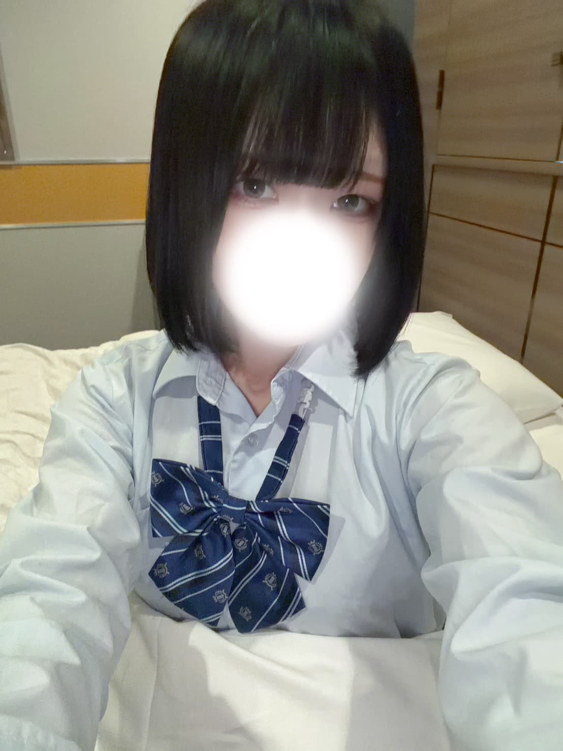 はなびは青いリボンの制服を着て、ベッドで微笑んでいます。