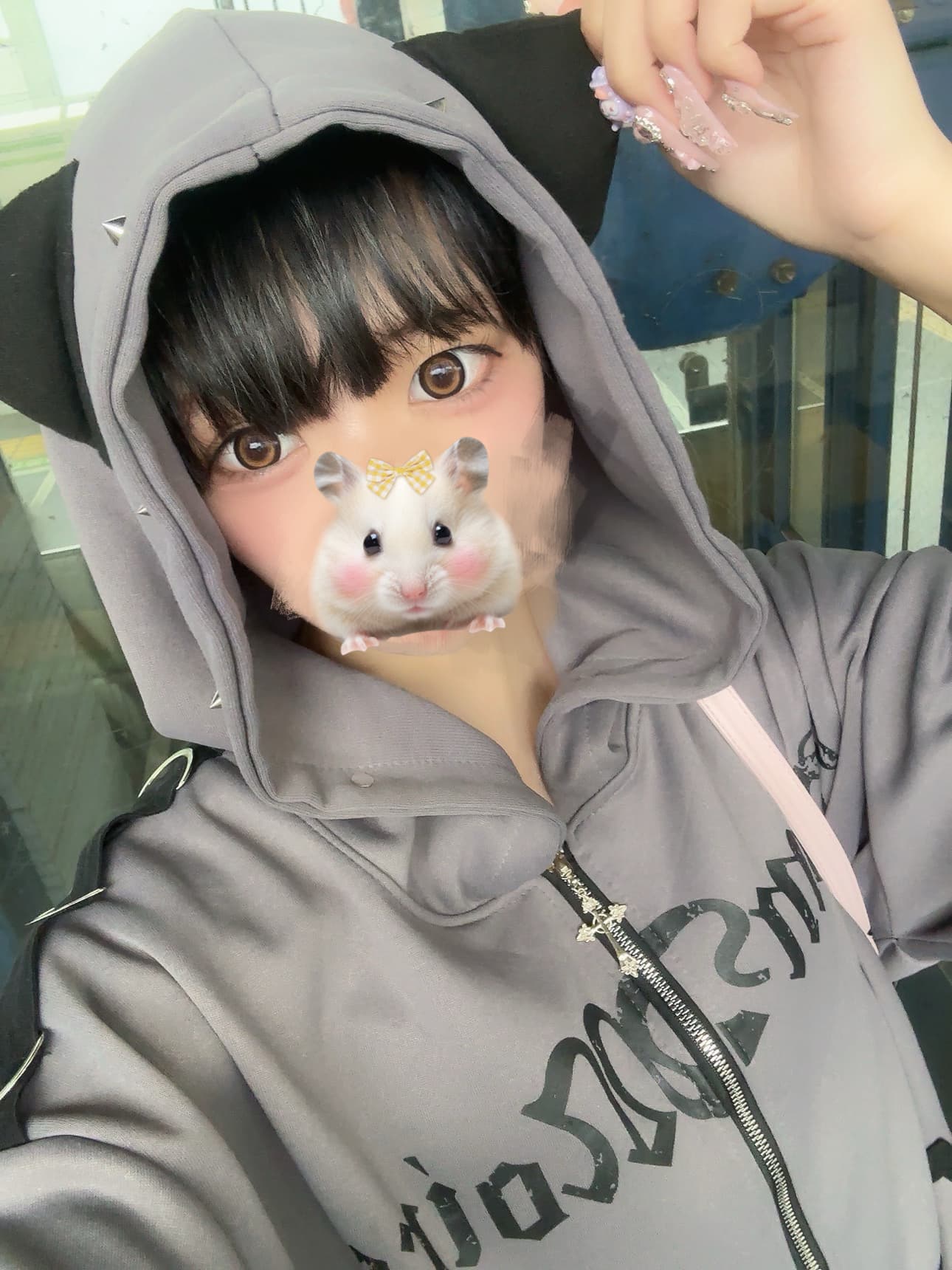 まなつがフード付きのカジュアルな服を着て、猫耳の帽子をかぶり微笑んでいる。