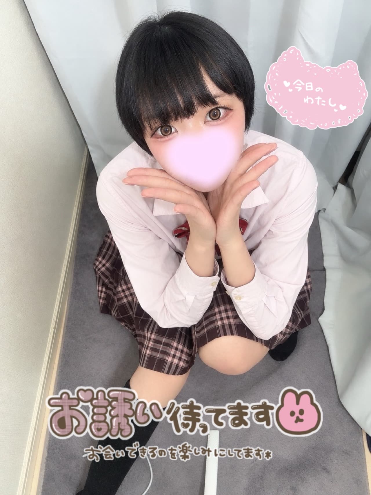 まなつが微笑みながら、制服姿で座っている写真です。