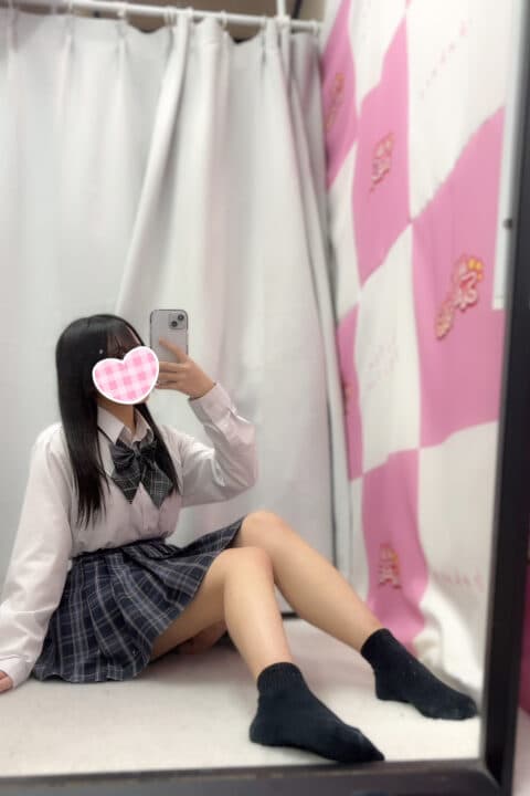 こころが白いシャツでスカートを着て鏡越しに微笑んでいる。