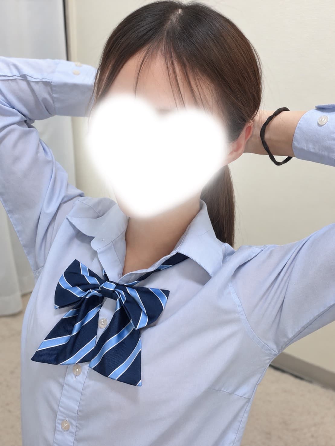 ななは青シャツにストライプのリボンを着用し、微笑みを浮かべている。
