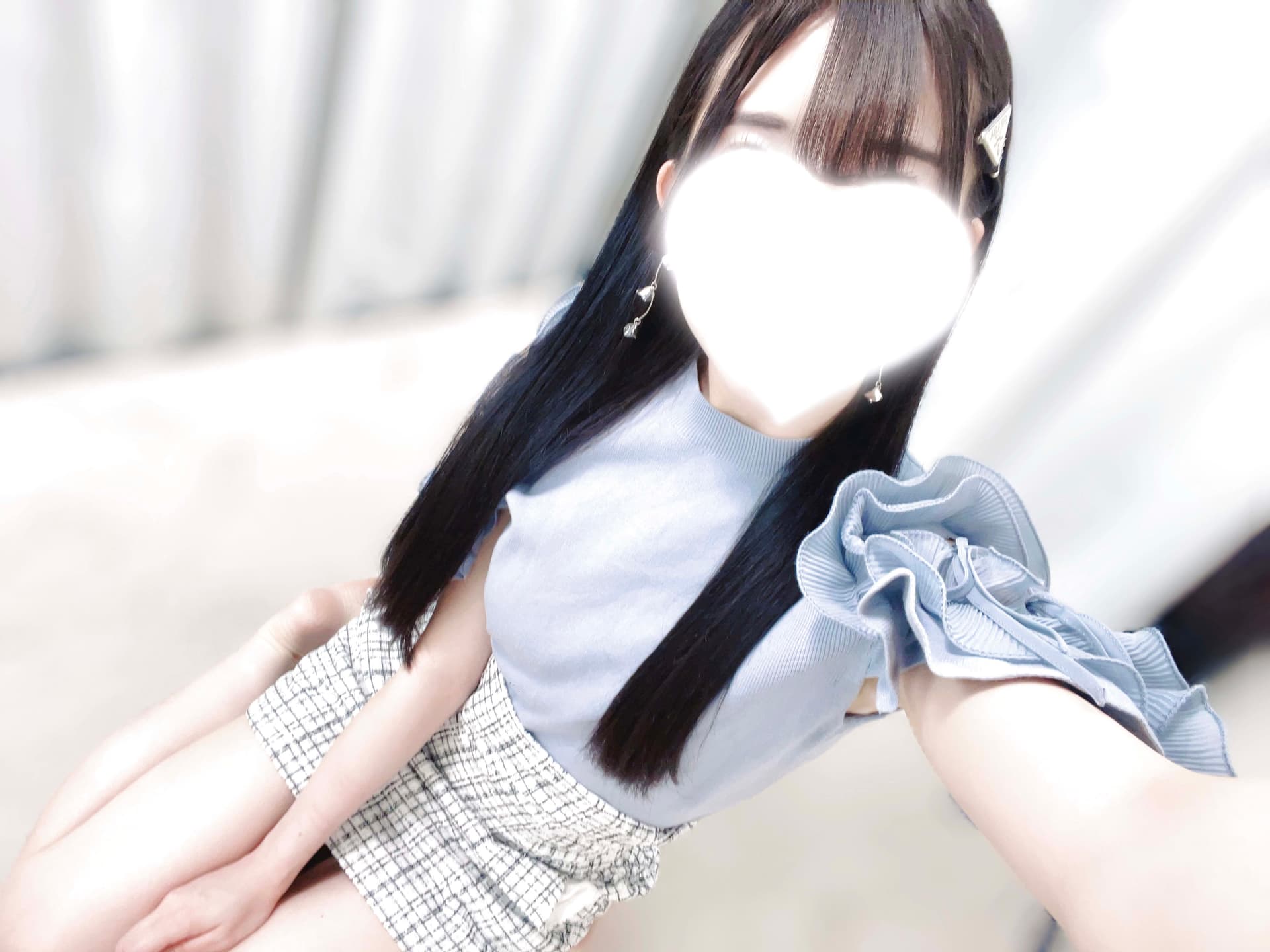 さゆのは青いトップスとチェックのスカートを着て微笑んでいる。